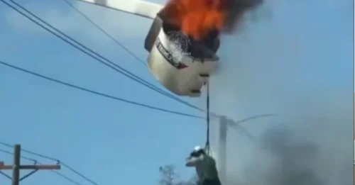 En una pesadilla laboral, se ve a un empleado de servicios públicos colgando de una máquina en llamas.