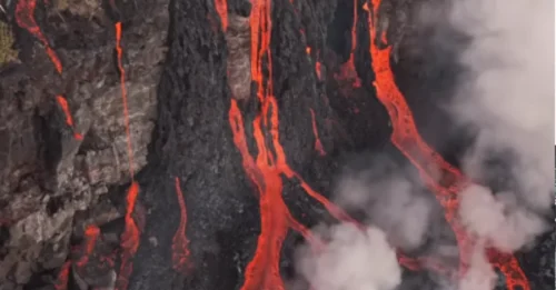 LAVA CONTRA AGUA! Impresionantes imágenes muestran cómo la lava ardiente avanza lentamente por la carretera y se encuentra con el océano tras la erupción de un volcán en una isla tropical.